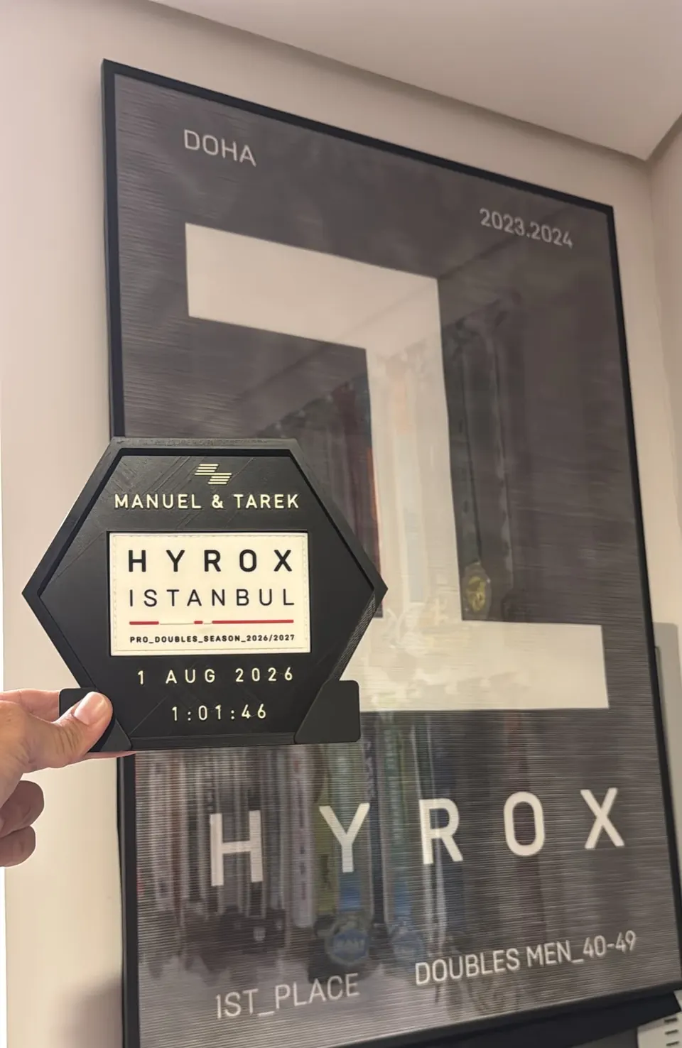HYROX Istanbul — Doubles Hex In Hand — Black hex display with white race plate and gold lettering.