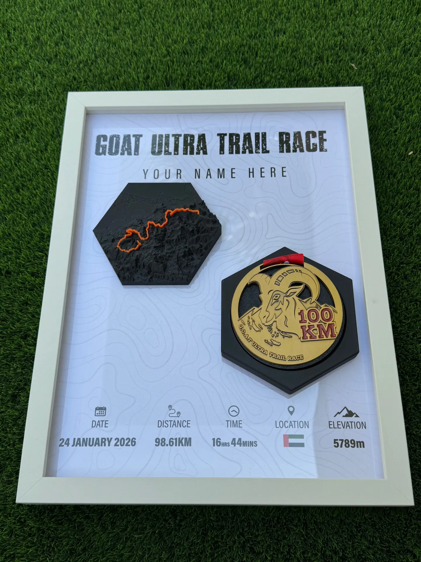 GOAT ULTRA TRAIL RACE — MEDAL FRAME — Shadow-box frame with hex relief and 100KM finisher medal.
