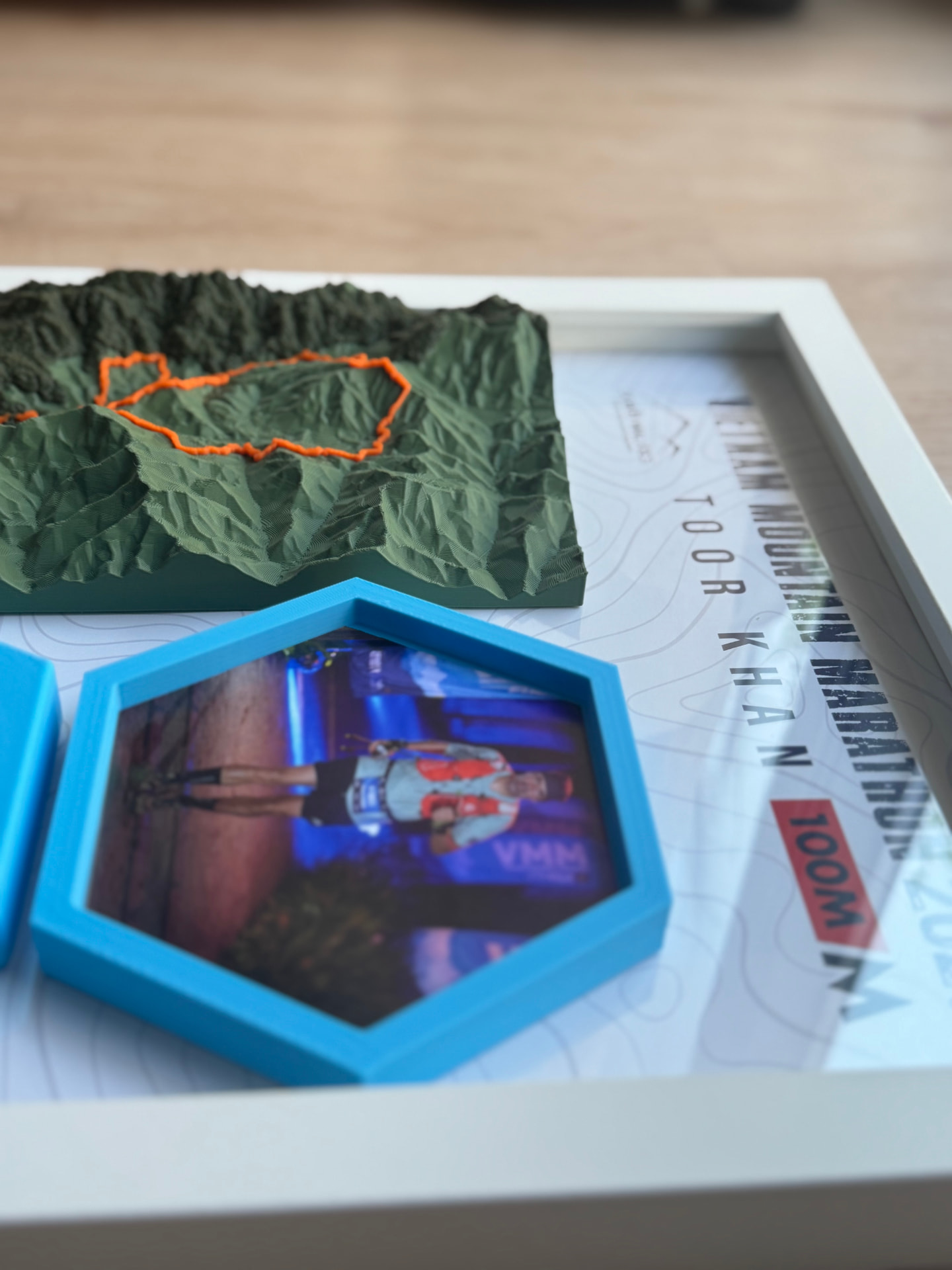 Vietnam Mountain Marathon 2026 — Finisher Photo — The finisher photo in a blue hex mount beside the printed relief.