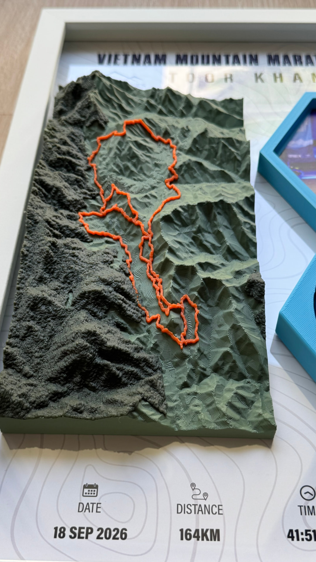 Vietnam Mountain Marathon 2026 — 3D Relief — Printed elevation contours of the 164KM course with the raised orange trail line.